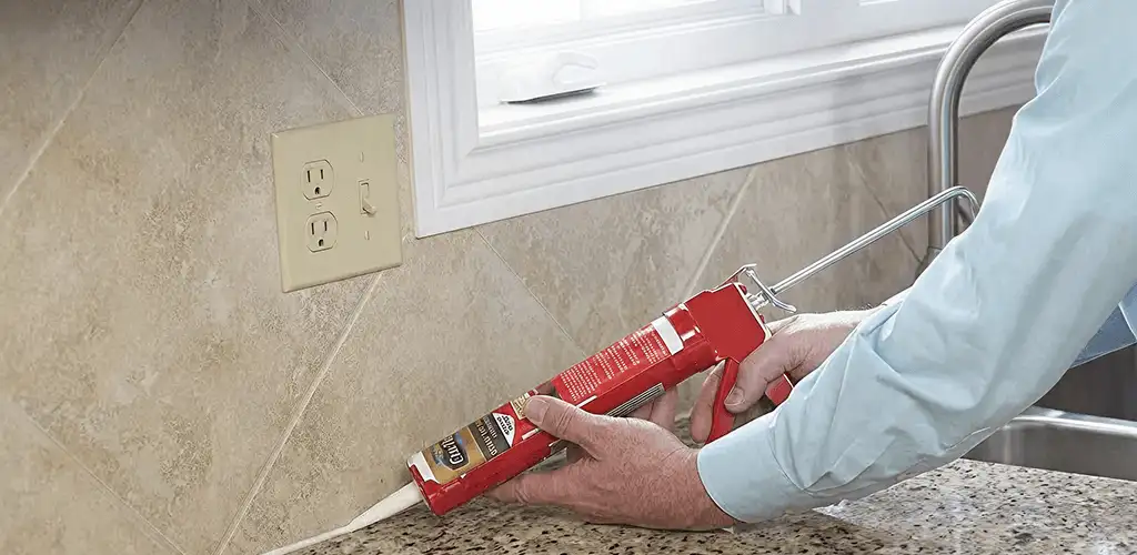 Handyman applying caulk along a kitchen backsplash and countertop seam in San Antonio, TX