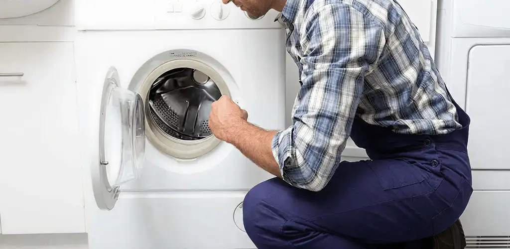 Handyman inspecting a dryer drum and internal parts for repair in San Antonio, TX