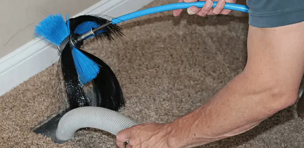 Dryer vent cleaning technician brushing lint from a vent line in San Antonio, TX