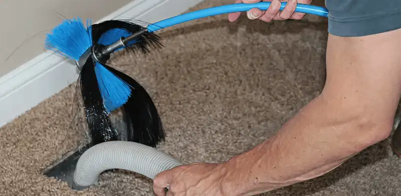 Dryer vent cleaning technician brushing lint from a vent line in San Antonio, TX