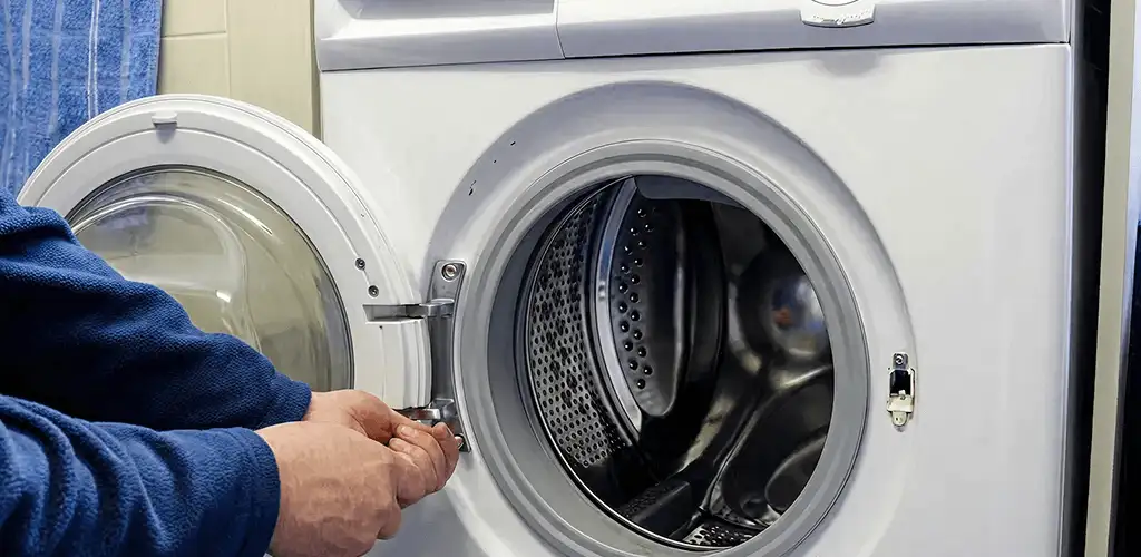 Washing machine repair handyman checking a front-load washer door and latch in San Antonio, TX