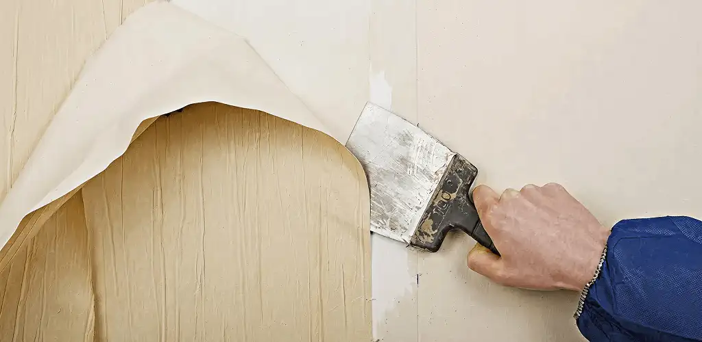 Handyman removing wallpaper with a scraper for wall preparation in San Antonio, TX