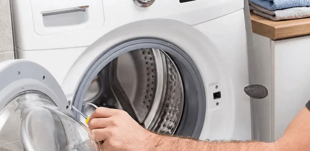 Handyman repairing a front-load washing machine and inspecting the drum in San Antonio, TX