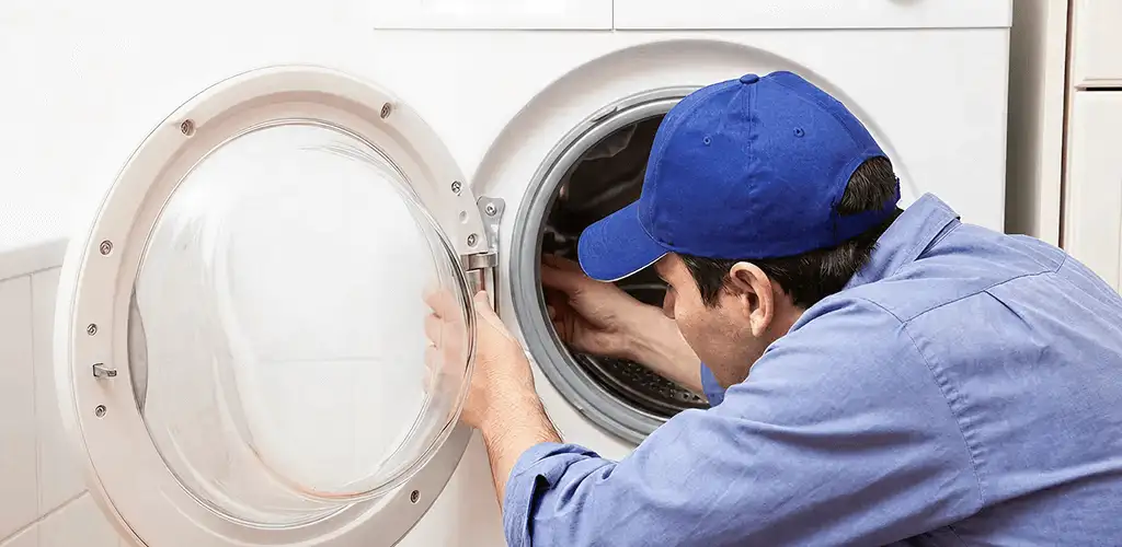 Washing machine repair handyman inspecting a front-load washer drum in San Antonio, TX