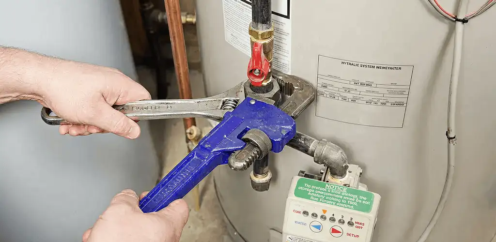 Water heater repair technician tightening the shutoff valve and supply line in San Antonio, TX